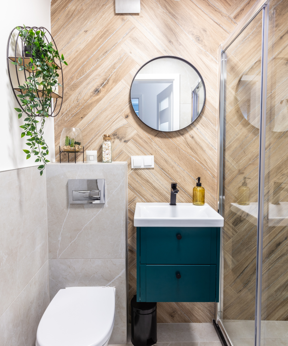 Stylish small bathroom with a blue vanity, glass shower, and patterned tile floor.